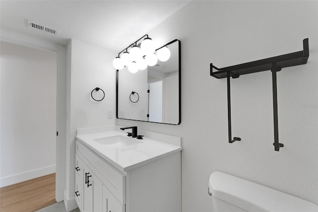 bathroom with hardwood / wood-style floors, vanity, and toilet