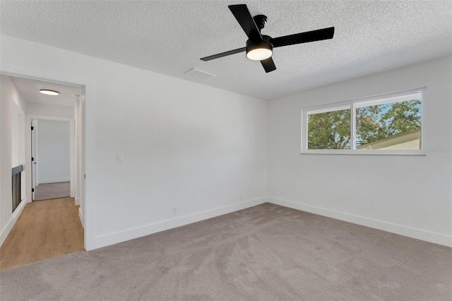 carpeted empty room featuring ceiling fan and a textured ceiling