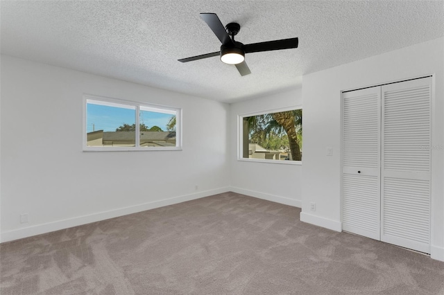 unfurnished bedroom featuring a textured ceiling, ceiling fan, light carpet, and a closet