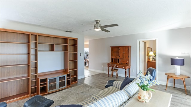 living room featuring ceiling fan, wood-type flooring, and a textured ceiling