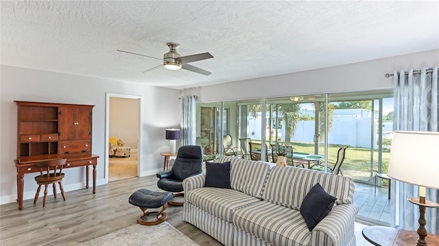 living room featuring ceiling fan, light hardwood / wood-style floors, and a textured ceiling