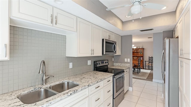 kitchen with sink, appliances with stainless steel finishes, light tile patterned flooring, light stone counters, and white cabinetry