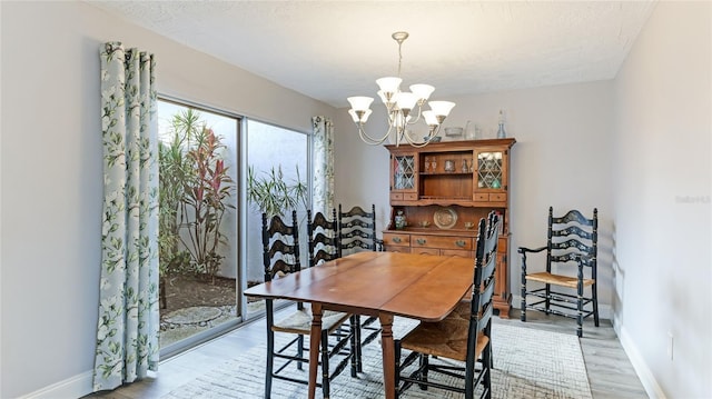 dining room with a textured ceiling, light hardwood / wood-style floors, and a notable chandelier