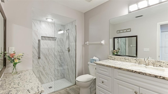 bathroom featuring a tile shower, vanity, hardwood / wood-style flooring, and toilet