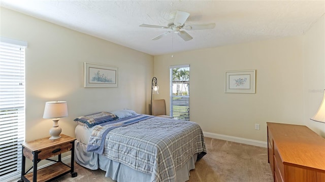 bedroom with ceiling fan, light carpet, and a textured ceiling