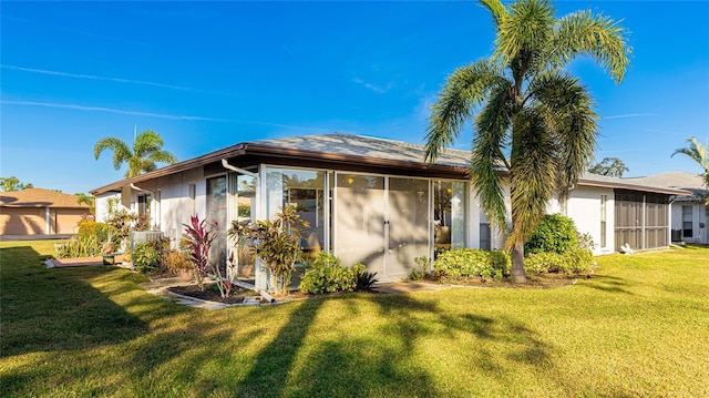 rear view of house featuring a sunroom and a yard