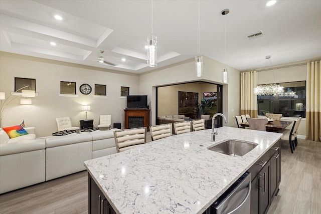 kitchen with a center island with sink, hanging light fixtures, light hardwood / wood-style floors, and sink