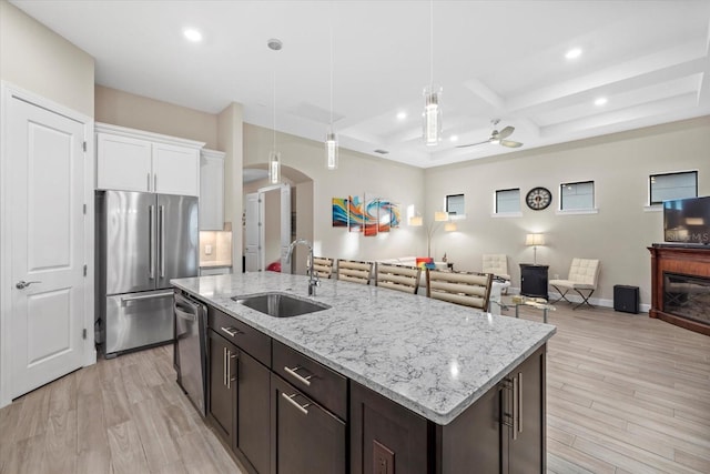 kitchen featuring ceiling fan, sink, hanging light fixtures, appliances with stainless steel finishes, and light wood-type flooring