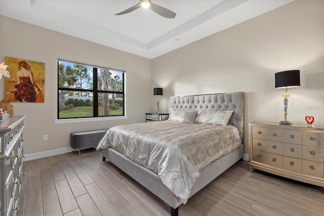 bedroom featuring a tray ceiling, light hardwood / wood-style flooring, and ceiling fan