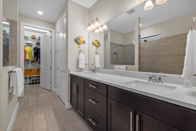 bathroom with tiled shower and vanity