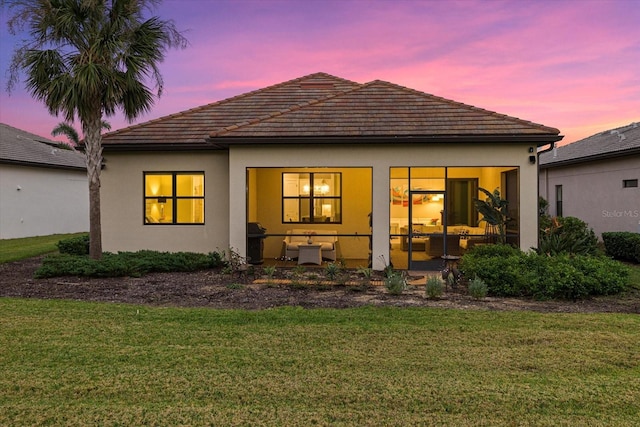 back house at dusk featuring a yard