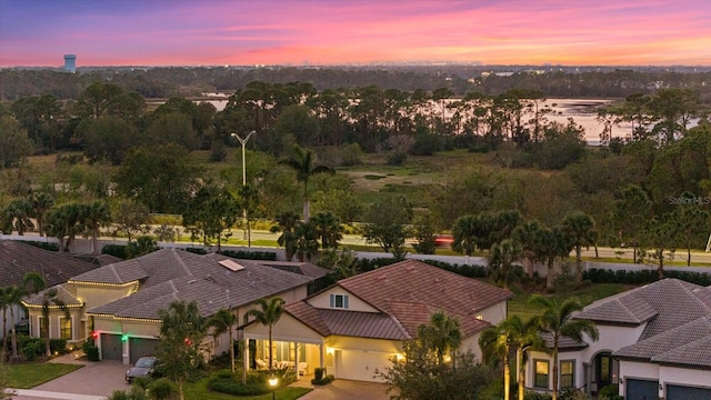 aerial view at dusk featuring a water view