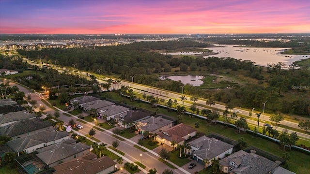 aerial view at dusk featuring a water view