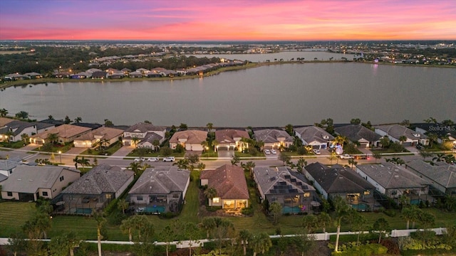 aerial view at dusk featuring a water view