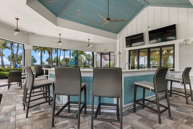 exterior space with high vaulted ceiling, kitchen peninsula, ceiling fan, white cabinetry, and wood ceiling