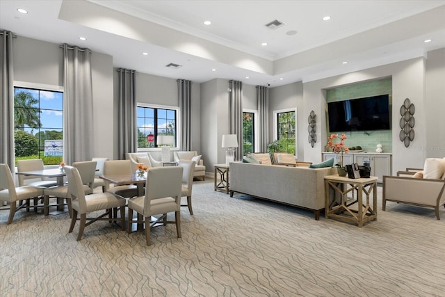 living room with a healthy amount of sunlight, a raised ceiling, and ornamental molding