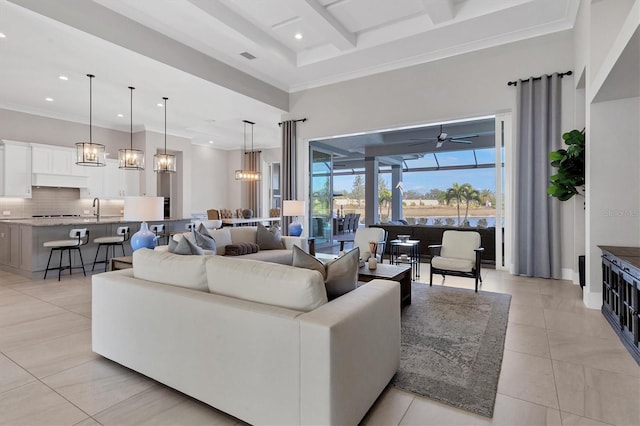 tiled living room with ceiling fan, ornamental molding, and sink