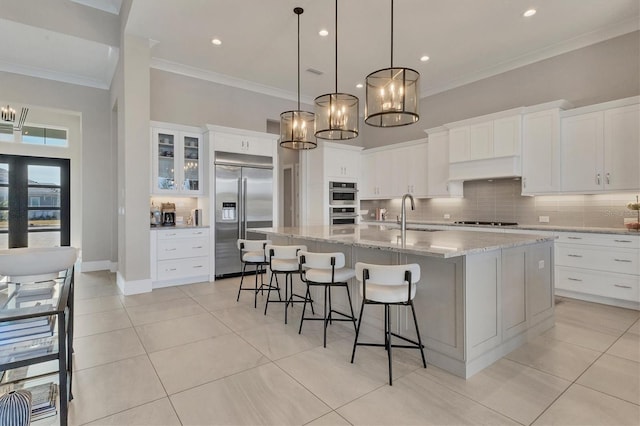 kitchen featuring stainless steel appliances, sink, white cabinetry, a large island, and light tile patterned flooring