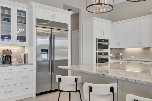 kitchen with pendant lighting, backsplash, a kitchen bar, and stainless steel appliances