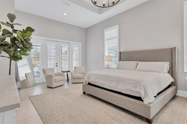 bedroom featuring light tile patterned floors, french doors, and an inviting chandelier