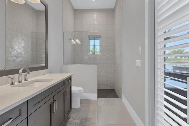 bathroom with tile patterned flooring, vanity, tiled shower, and a wealth of natural light