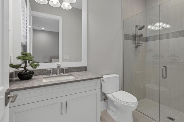 bathroom featuring vanity, a shower with shower door, and toilet