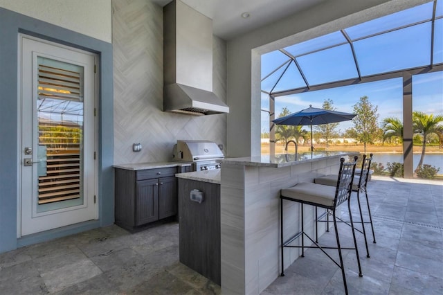 view of patio featuring area for grilling, a lanai, a bar, a water view, and a grill