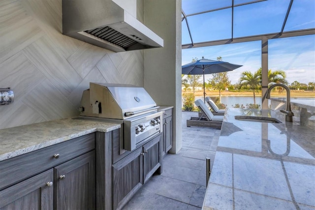 view of patio / terrace with area for grilling, a water view, exterior kitchen, and sink