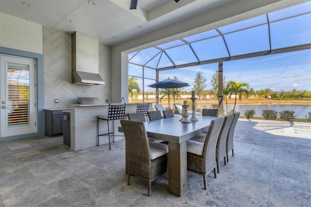 view of patio / terrace with exterior bar, a water view, glass enclosure, and exterior kitchen