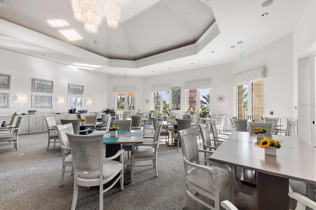 dining room featuring a raised ceiling, carpet floors, a high ceiling, and a wealth of natural light