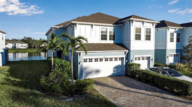 view of front of home with a water view, a garage, and a front lawn