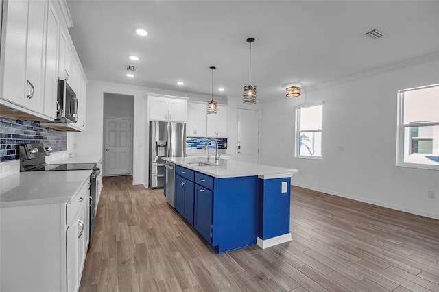 kitchen featuring blue cabinetry, stainless steel appliances, white cabinets, and a wealth of natural light