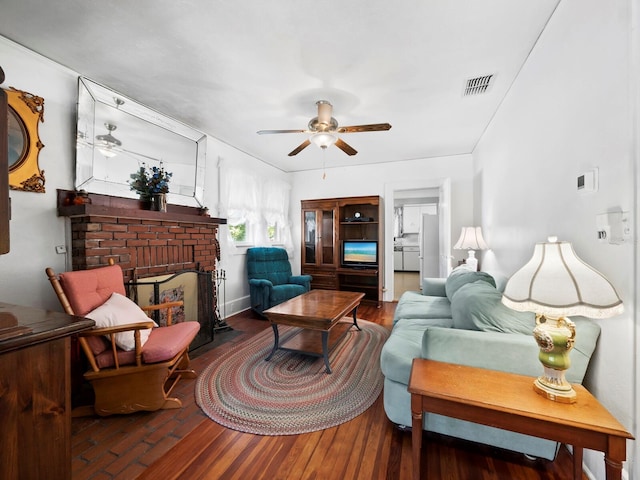 living room featuring ceiling fan, wood-type flooring, and a brick fireplace