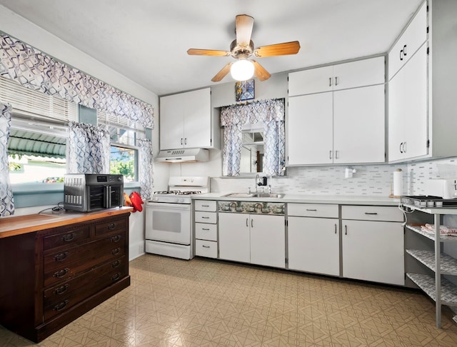 kitchen with white cabinets, ceiling fan, white gas range, and sink