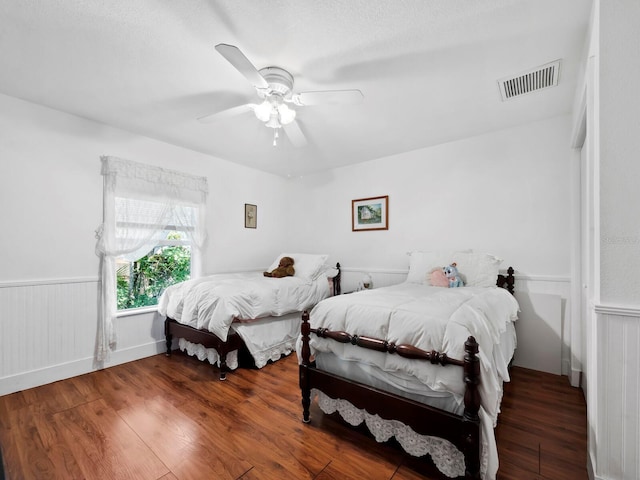 bedroom with a textured ceiling, ceiling fan, and dark wood-type flooring