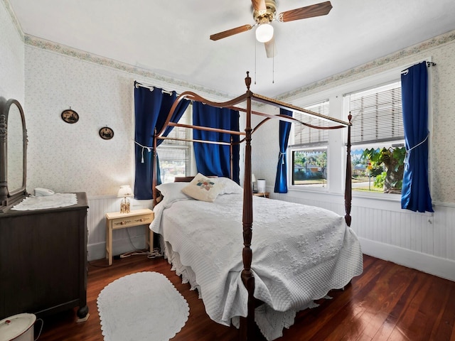 bedroom with ceiling fan, wooden walls, and dark hardwood / wood-style floors