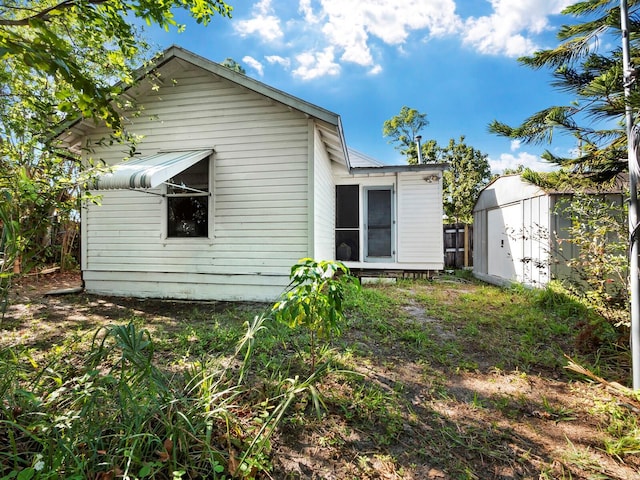 rear view of property featuring a storage unit