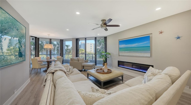 living room featuring floor to ceiling windows, ceiling fan, and light hardwood / wood-style flooring