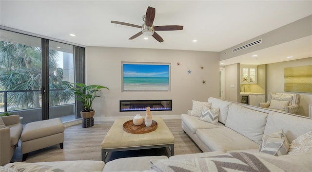 living room with ceiling fan, light wood-type flooring, and sink