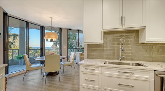 kitchen featuring plenty of natural light, white cabinetry, sink, and decorative light fixtures