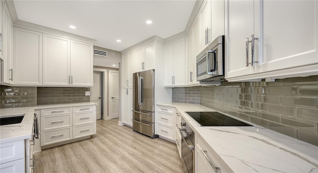 kitchen with white cabinets, light stone counters, and stainless steel appliances