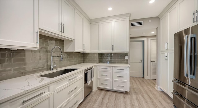 kitchen featuring light stone countertops, appliances with stainless steel finishes, sink, light hardwood / wood-style floors, and white cabinetry