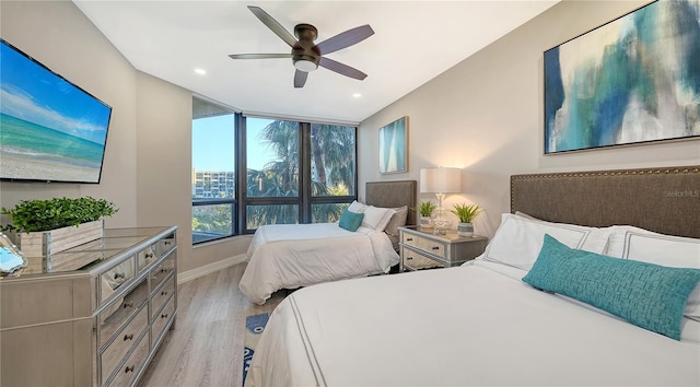 bedroom featuring ceiling fan, a wall of windows, and light hardwood / wood-style flooring