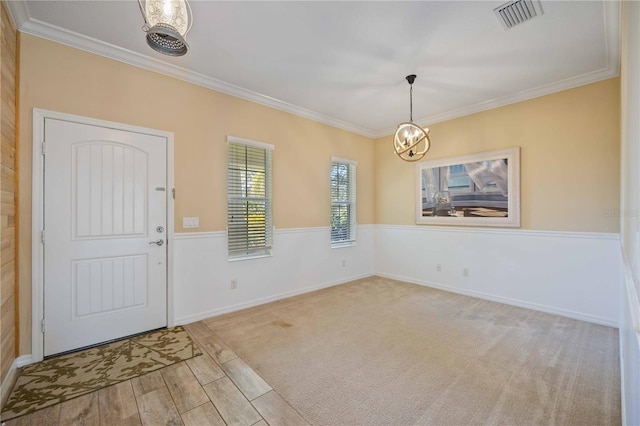 entrance foyer with light hardwood / wood-style floors, an inviting chandelier, and ornamental molding