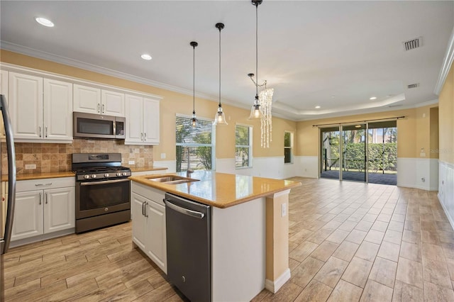 kitchen featuring sink, an island with sink, decorative light fixtures, white cabinetry, and stainless steel appliances