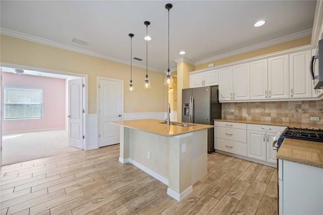 kitchen featuring a center island with sink, white cabinetry, hanging light fixtures, and sink