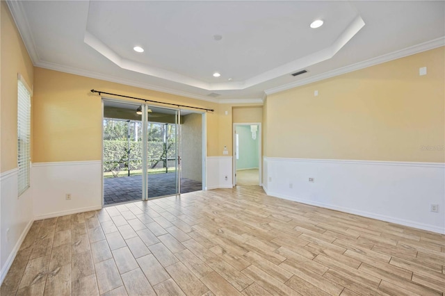 unfurnished room with a raised ceiling, crown molding, and light hardwood / wood-style flooring