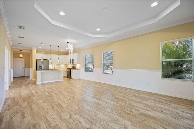 unfurnished living room with plenty of natural light, crown molding, and light hardwood / wood-style flooring