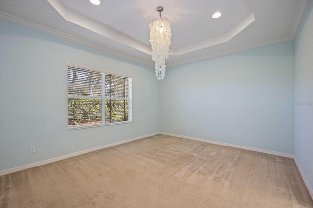 carpeted spare room featuring a raised ceiling, crown molding, and an inviting chandelier