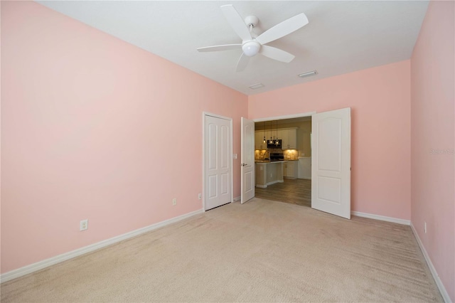 unfurnished bedroom featuring a closet, light colored carpet, and ceiling fan